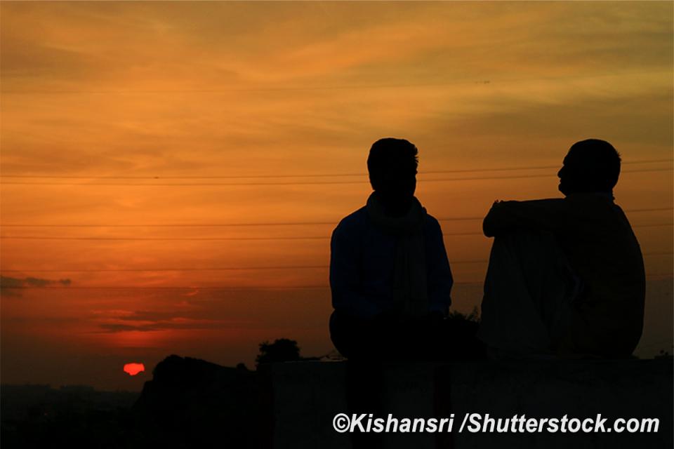 Silhouettes of a man and male teen engaged in conversation.